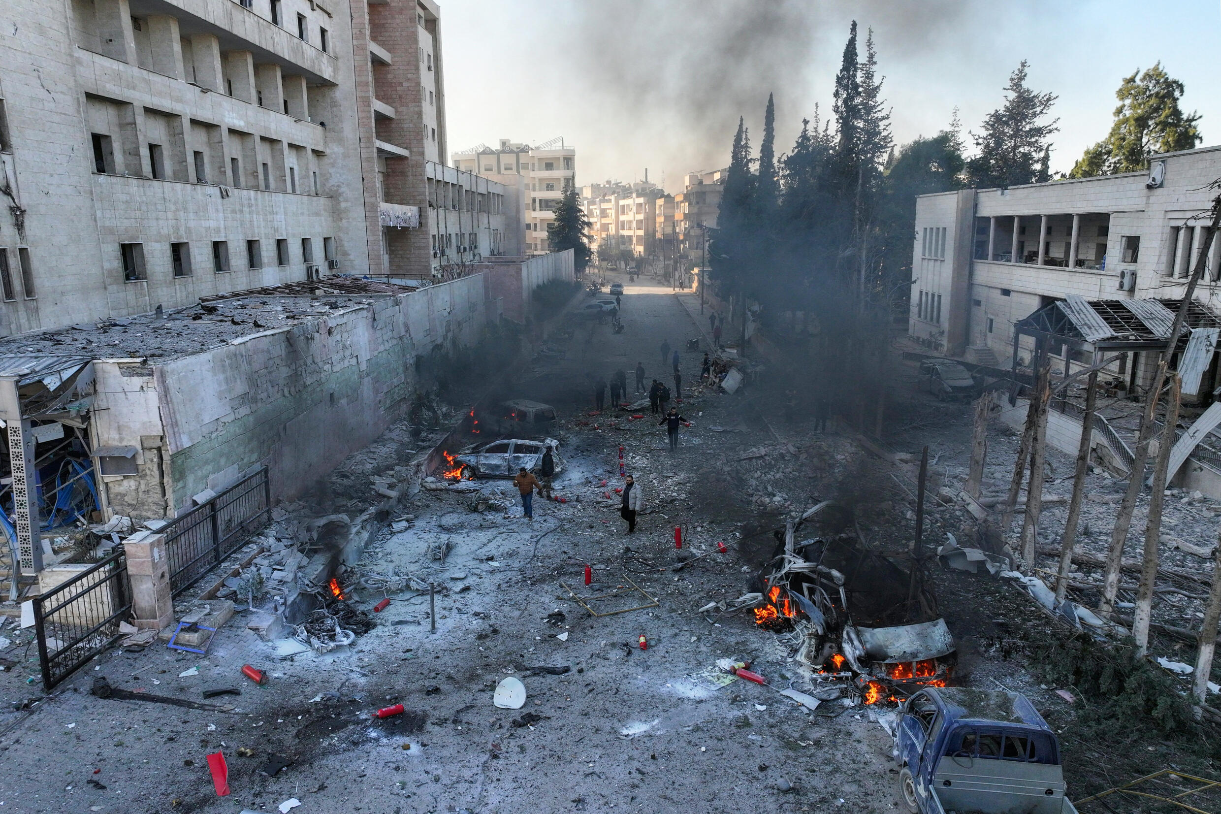 Une photo aérienne montre des personnes essayant d'éteindre des incendies après une frappe aérienne qui a visé la ville d'Idlib, au nord de la Syrie, tenue par les rebelles, le 2 décembre 2024.